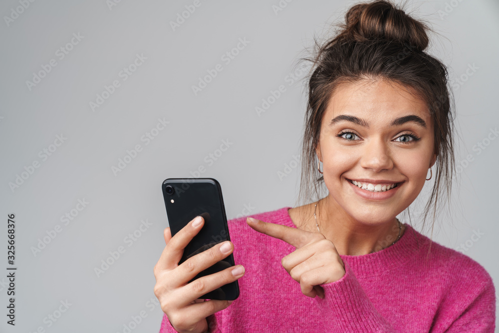 Image of excited beautiful woman pointing finger at cellphone Image of excited beautiful woman pointing finger at cellphone