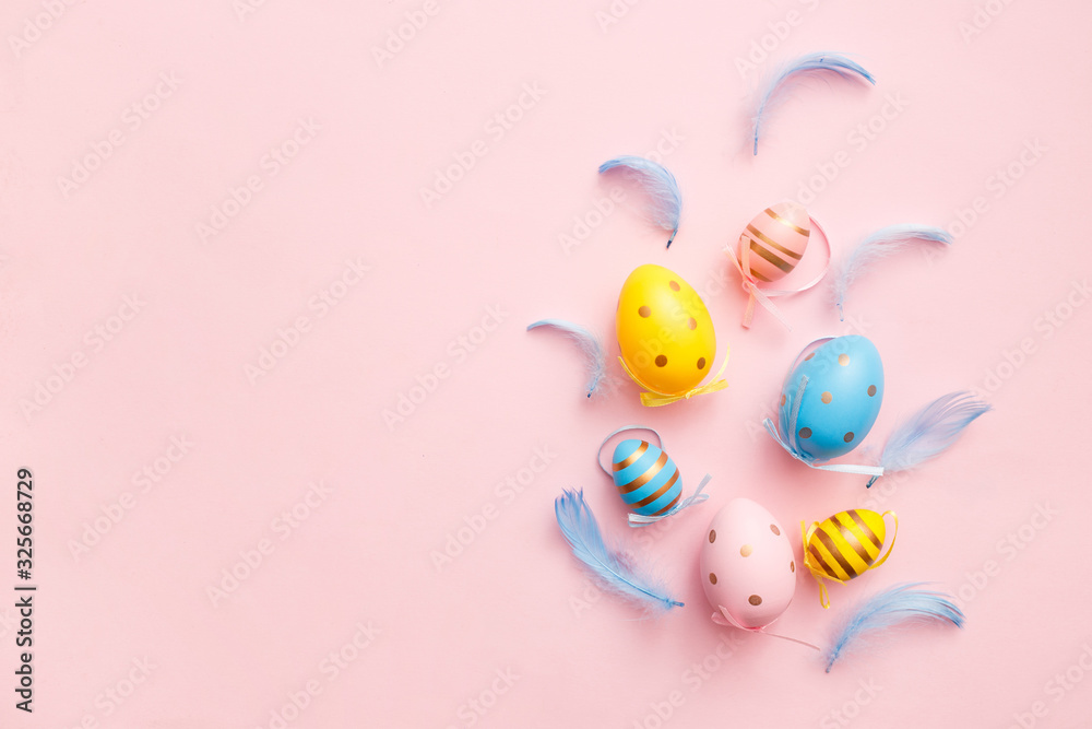 Easter colored eggs with feathers on pink pastel background. Happy Easter greeting card minimal concept. Top view, flat lay, copy space