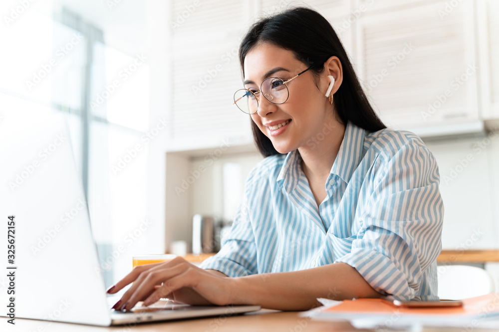 Woman using laptop computer and wireless earphones. Woman using laptop computer and wireless earphones.
