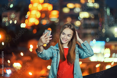 Teen girl on cityscape background making self portrait with her smart phone © paffy