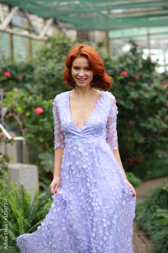 beautiful red-haired girl in arranger where azalea blooms in a colorful flying dress © Alina