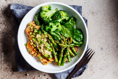 Vegan lunch bowl with quinoa, broccoli, asparagus and mushroom sauce in white bowl.