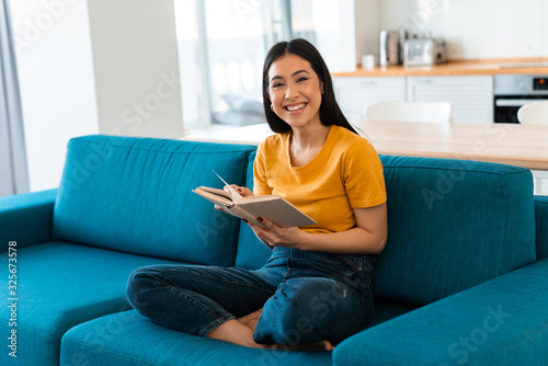 Brunette young woman on sofa indoors reading book.