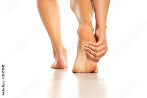 woman holding her painful foot on white