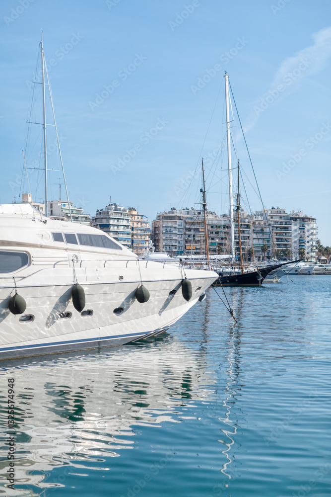 Pier with moored yachts in port. High class lifestyle. Luxury summer vacation. Balearic islands, Majorca. Maritime walking. Yachting sport. Marina with anchored sailboats. Houses on background. Pier with moored yachts in port. High class lifestyle. Luxury summer vacation. Balearic islands, Majorca. Maritime walking. Yachting sport. Marina with anchored sailboats. Houses on background.