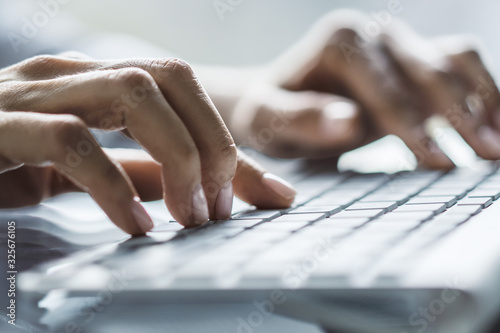 Woman hands typing on computer keyboard in sunny office, business and technology concept. Close up