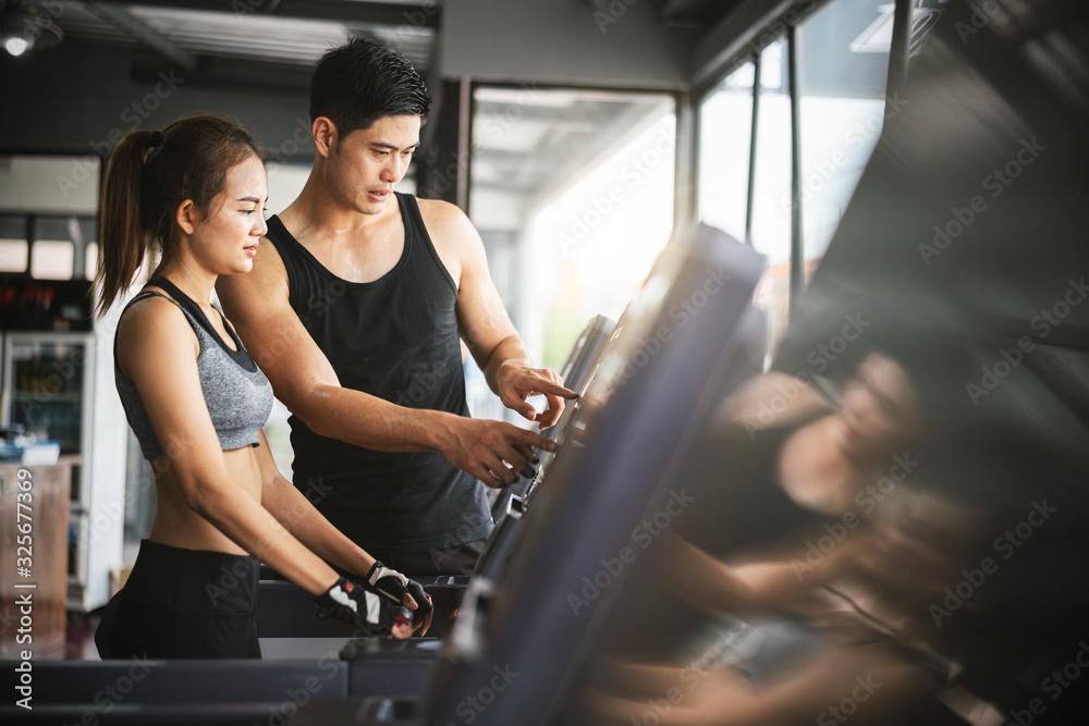 Asian man fitness trainer wearing sportswear helping and supporting his  customer workout treadmill running equipment for bodybuilding in her class, Fitness  gym concept Stock Photo