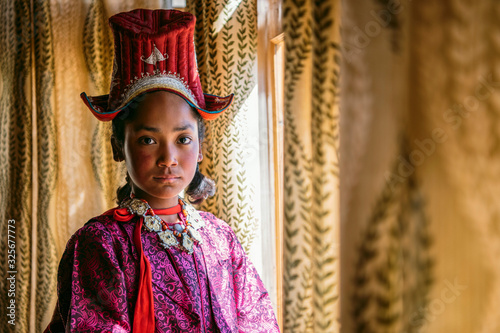 Portrait of a beautiful young girl in typical tibetan clothes with hat in Ladakh, Kashmir, India