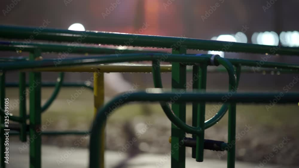Wet carousel spinning at empty children's playground in city park on an autumn night. Wet carousel spinning at empty children's playground in city park on an autumn night.