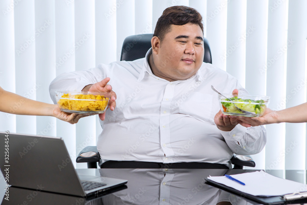 Fat Asian businessman preferring salad over chips Fat Asian businessman preferring salad over chips