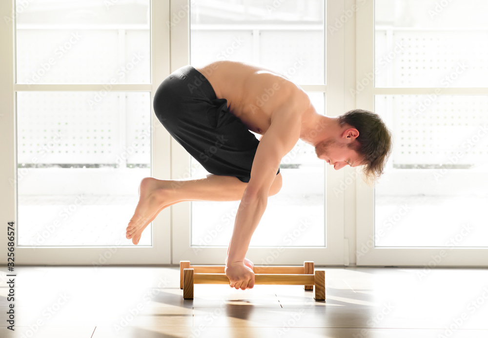 Young man doing a calisthenics crow pose Young man doing a calisthenics crow pose
