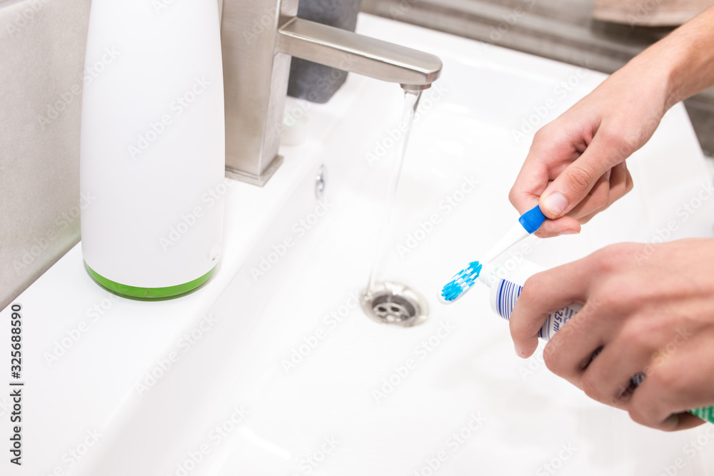Toothbrush with toothpaste in the guy's hand on the background of the washbasin. Toothbrush with toothpaste in the guy's hand on the background of the washbasin.