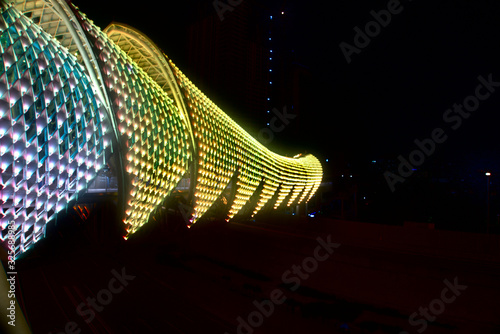 Pedestrian bridge from side with green and yellow light at night