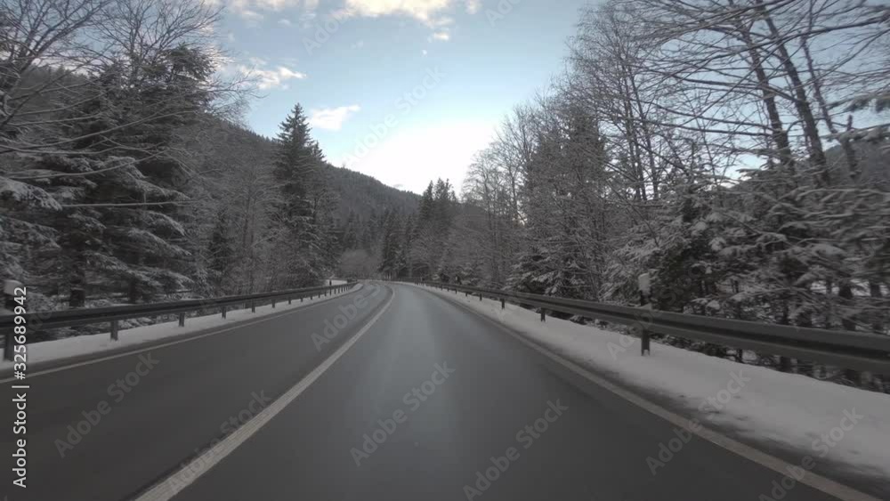 FRONT DRIVING PLATE Car driving on road through snowy landscape towards mountains FRONT DRIVING PLATE Car driving on road through snowy landscape towards mountains