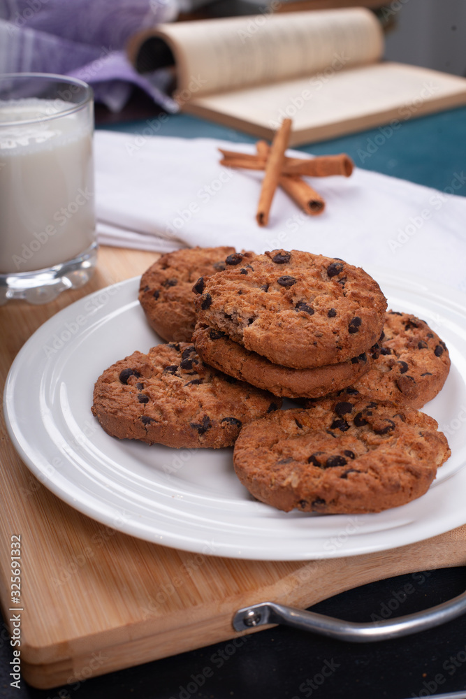 Oatmeal cookies with chocolate chips and a glass of milk on a wooden board Oatmeal cookies with chocolate chips and a glass of milk on a wooden board