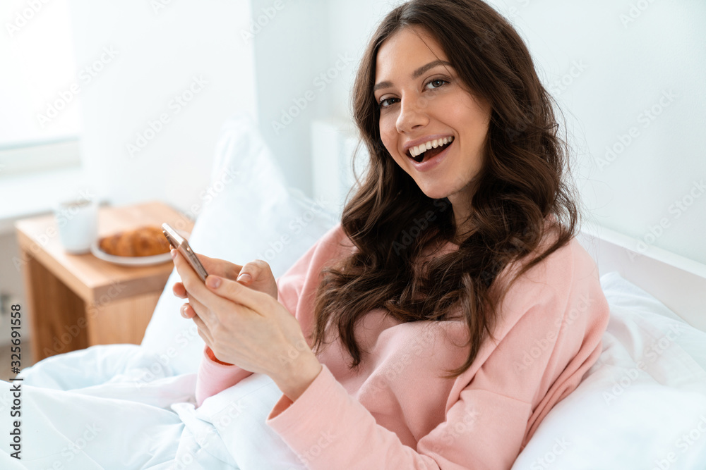 Woman indoors at home using mobile phone. Woman indoors at home using mobile phone.