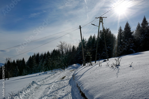 Fototapeta Naklejka Na Ścianę i Meble -  road in a mountain village in the winter with sun rays