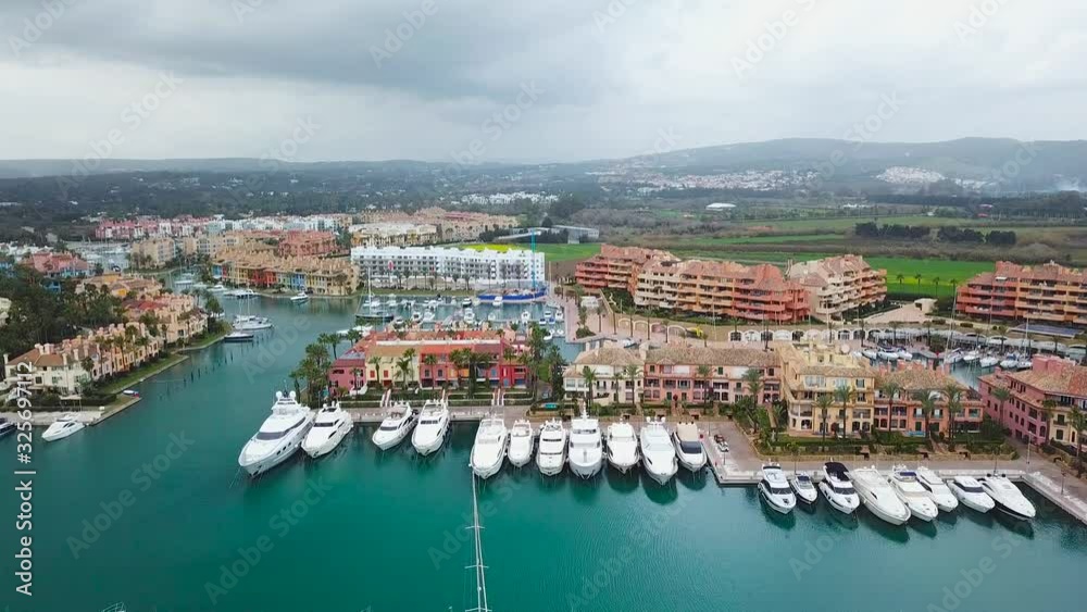 Unique generic aerial view of exclusive Sotogrande Bay - Costa del Sol. Cloudy day and rainy , beautiful sky colours. Luxury real estate and yacht. Famous location. 