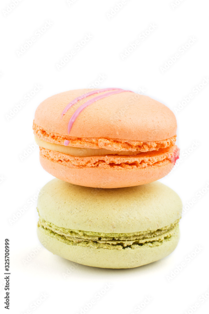 Orange and green macarons or macaroons cakes isolated on white background, side view. Orange and green macarons or macaroons cakes isolated on white background, side view.
