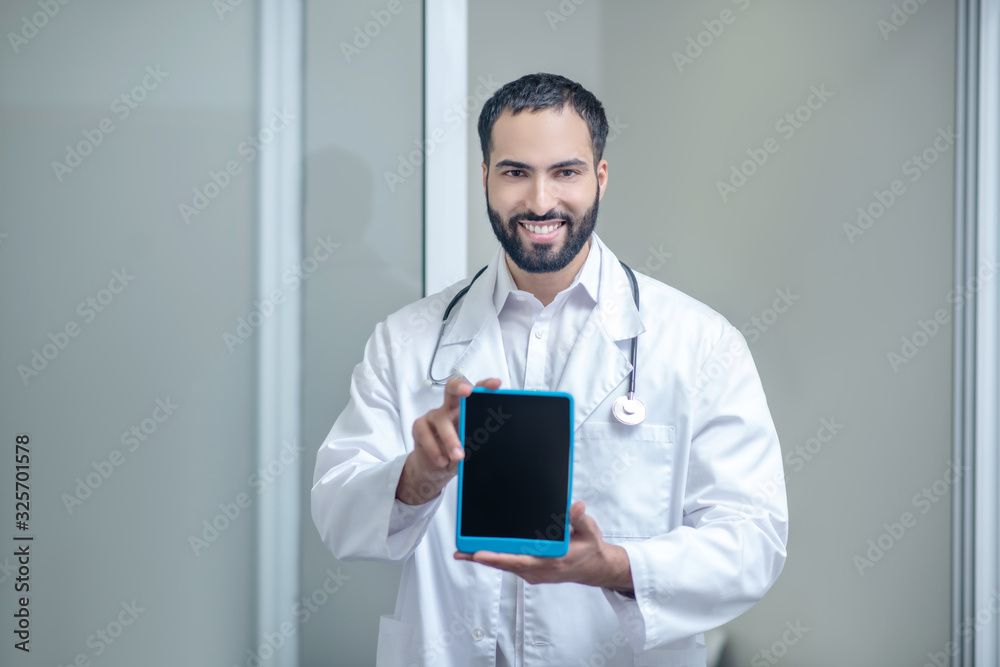 Male doctor in a white robe holding a tablet in his hands Male doctor in a white robe holding a tablet in his hands