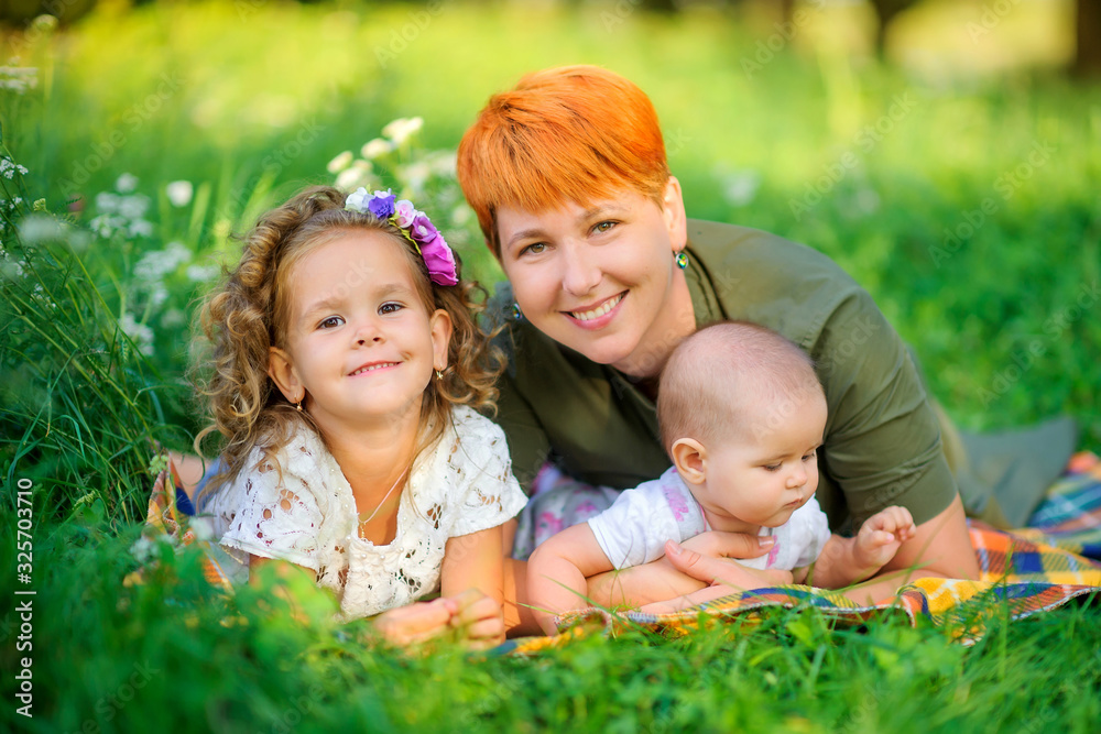 Happy family. Mom with her beloved daughters is resting in a beautiful park at sunset, family time. Happy family. Mom with her beloved daughters is resting in a beautiful park at sunset, family time.