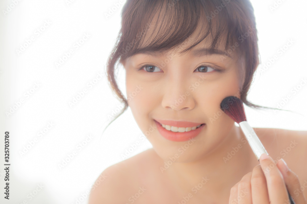 Beauty portrait young asian woman smile with face looking mirror applying makeup with brush cheek in the bedroom, beautiful of girl holding blusher, skin care and cosmetic concept. Beauty portrait young asian woman smile with face looking mirror applying makeup with brush cheek in the bedroom, beautiful of girl holding blusher, skin care and cosmetic concept.