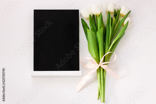 Black chalk board mockup with tulip flowers on white background. Blackboard menu with easel  spring sales. Copy space frame adding text content. Blank inscription template. Education training display.