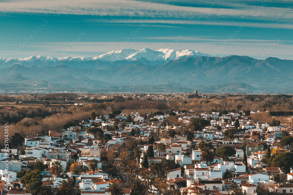 Traditional Spanish village cityscape with white houses in front of The Pyrenees with snow caps, travel destination for vacations, popular landmark