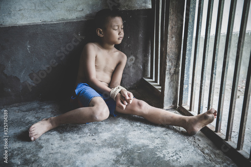 Victim boy with hands tied up with rope in emotional stress and pain,  kidnapped, abused, hostage,  afraid, restricted, trapped,  struggle,  Stop violence against children and trafficking Concept Fototapete
