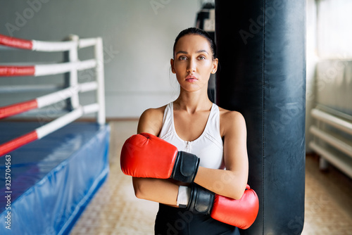 Sporty young woman wearing boxing gloves posing in gym © GVS