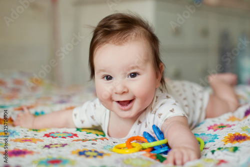 Cute baby boy lying on the bed and play with his toys