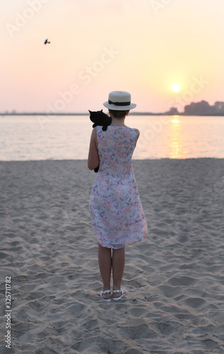 vertical sunset photo of a beautiful young girl with a black cat