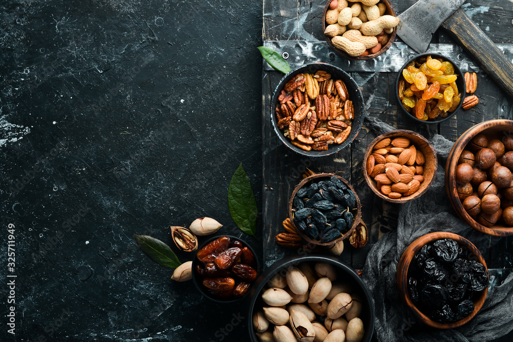 Set of nuts and dried fruits and berries on a black stone background. Top view. Free space for your text. Set of nuts and dried fruits and berries on a black stone background. Top view. Free space for your text.
