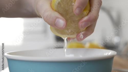 Slow motion shot as squeezing a lemon in to a bowl in the kitchen. photo