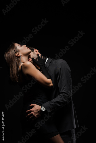 bearded man kissing attractive woman isolated on black
