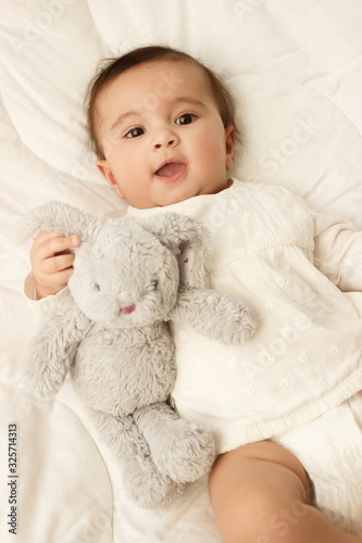 Little cute baby girl on the blanket with a bunny toy