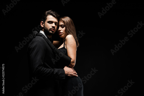 handsome man hugging beautiful woman in dress isolated on black