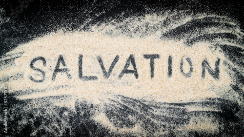 Obraz na plátně Flat lay of SALVATION word written on white sand