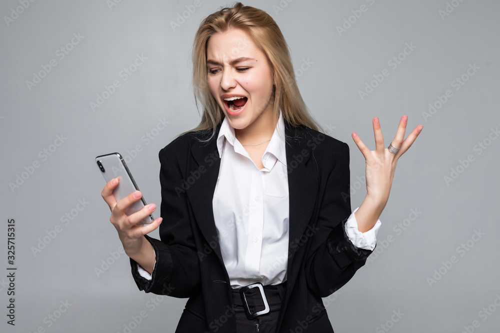 Surprised pretty businesswoman chatting by phone standing isolated over white background. Surprised pretty businesswoman chatting by phone standing isolated over white background.