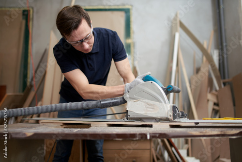 Male in white gloves works on jigsaw in workshop