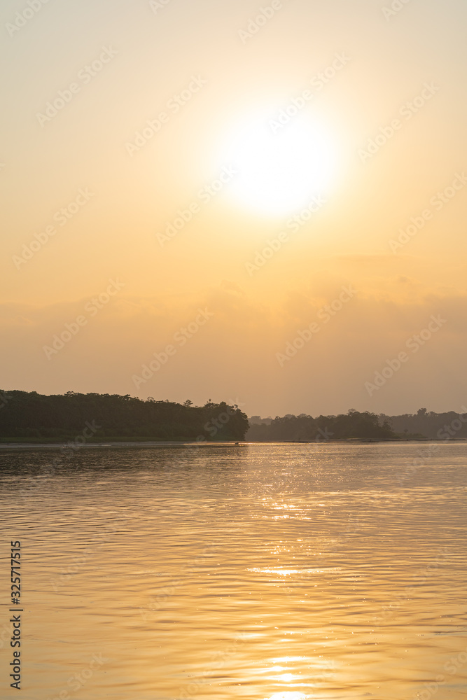 Naklejka premium Amazon rainforest sunset during a boat trip with a reflection of the trees in the water. Puerto Francisco de Orellana. Ecuador. South America.