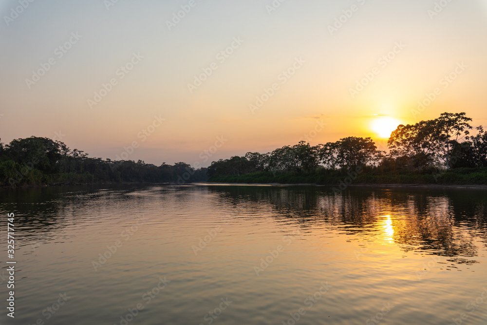Amazon rainforest sunset during a boat trip with a reflection of the trees in the water. Puerto Francisco de Orellana. Ecuador. South America.