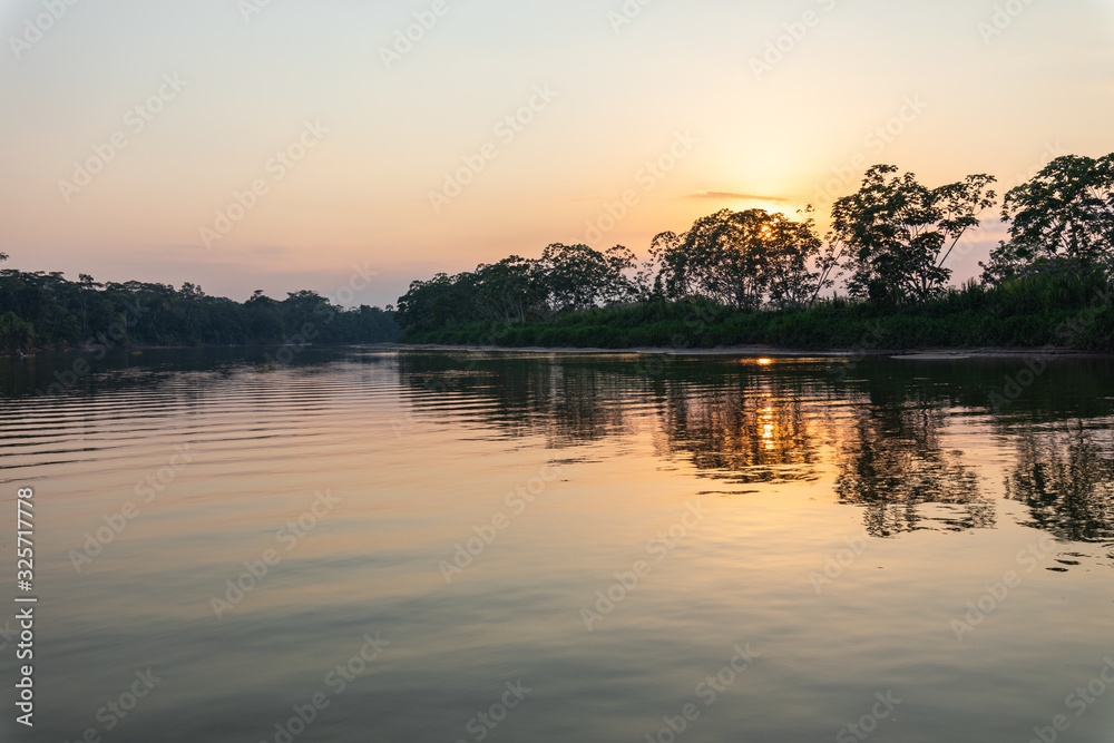 Amazon rainforest sunset during a boat trip with a reflection of the trees in the water. Puerto Francisco de Orellana. Ecuador. South America.