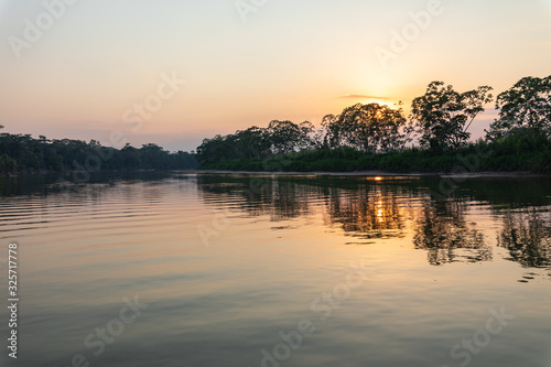 Amazon rainforest sunset during a boat trip with a reflection of the trees in the water. Puerto Francisco de Orellana. Ecuador. South America. © Curioso.Photography