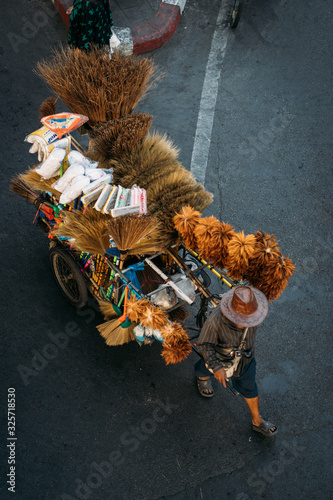 Top view of street vendor pulling a cart with brooms, dusters and other cleaning supplies, selling them on a street in Bangkok, Thailand. photo