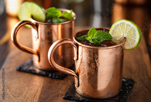 Photography two moscow mules in copper cup wih lime and mint garnish