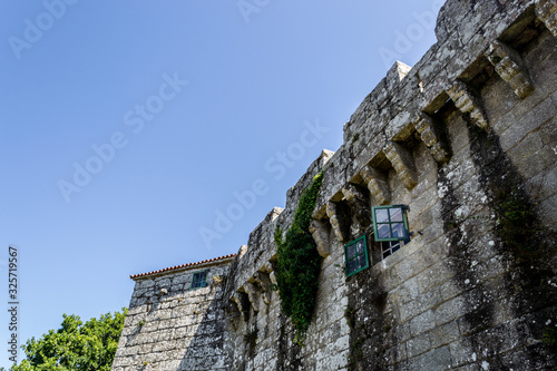 Photography of the wall of a castle with an opened green window in a blue sky background
