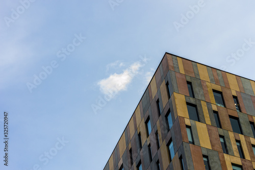 Photography of the corner of a colourful building with many windows and a blue sky background