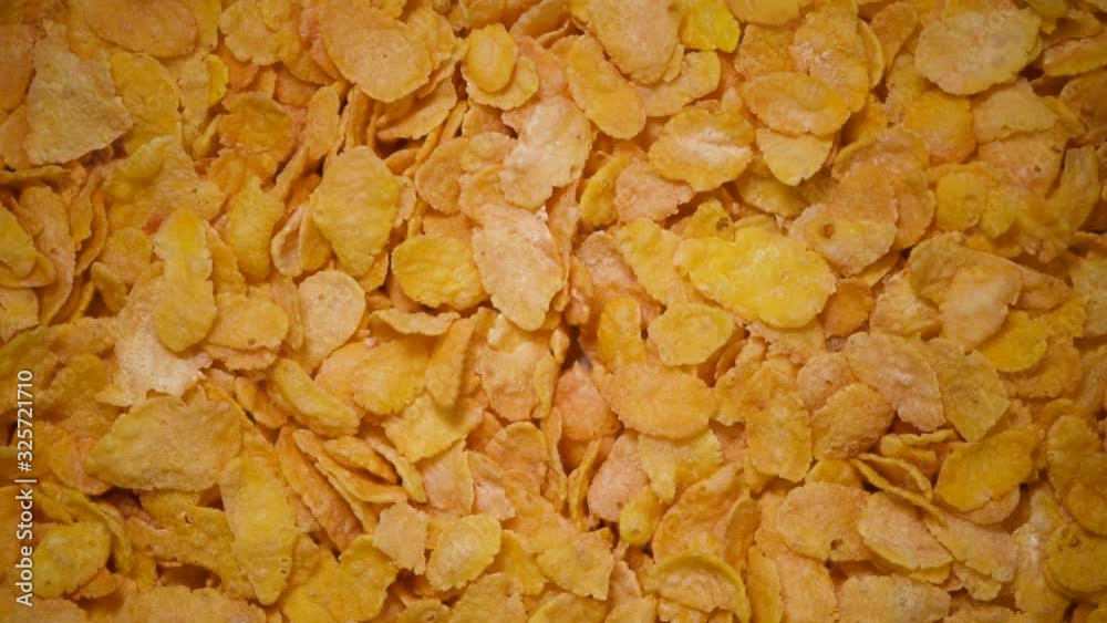 Golden corn flakes for breakfast on rotating background. Food ingredient background. Top view, healthy lifestyle concept. Vegan healthy nutrition Golden corn flakes for breakfast on rotating background. Food ingredient background. Top view, healthy lifestyle concept. Vegan healthy nutrition