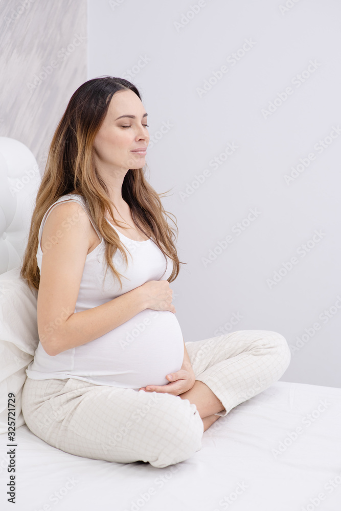 Pregnant woman practicing Yoga in the beadroom. Pregnant woman practicing Yoga in the beadroom.